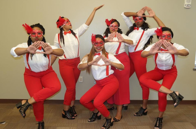 Delta Sigma Theta - 6 female students dressed in red and white costumes with bow ties and suspenders